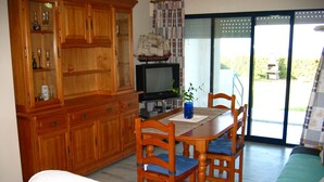 A dining area with a wooden table, chairs, and a television. - Canal Salinas, Bajo solo Familias (Xeraco Playa)