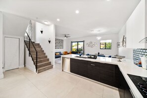Une cuisine moderne dotée d’un îlot central, de meubles de rangement aux couleurs sombres et d’un lave-vaisselle encastré.