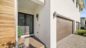 A modern house with a garage, a wooden exterior wall, and a small potted plant.