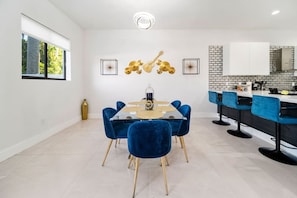 Un espace repas moderne avec une table en verre, des chaises en velours bleu et des touches dorées.