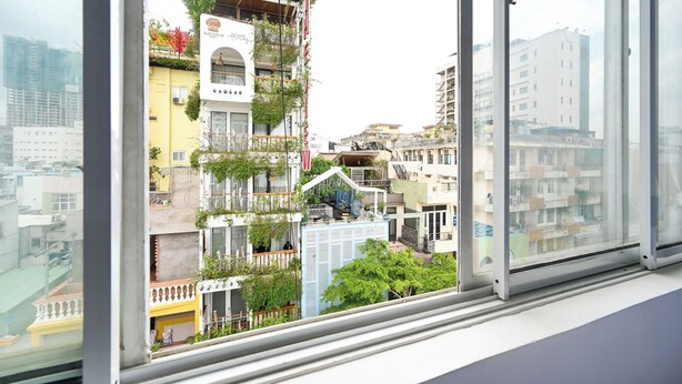 A multi-story building with balconies, some with plants, and a clear view of the surrounding urban area through a window. - Huyen Home (Ho Chi Minh City)