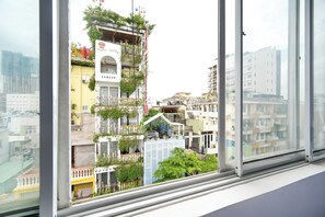 Un edificio de varios pisos con balcones, algunos con plantas, y una vista despejada del entorno urbano a través de un ventanal.