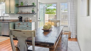 A dining area with a wooden table and chairs, a chandelier, and a view of the backyard through a glass door. - An Oasis Awaits You with Vineyard Views (McDonough)