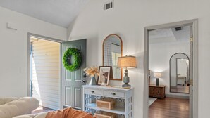 A living room with a sofa, a console table with a mirror, and a door with a wreath. - An Oasis Awaits You with Vineyard Views (McDonough)