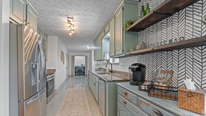 A kitchen with stainless steel appliances, a herringbone-patterned backsplash, and a decorative sign. - An Oasis Awaits You with Vineyard Views (McDonough)