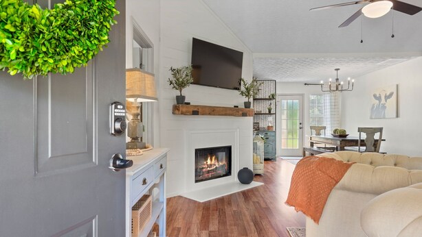 A living room with a fireplace, a sofa, and a TV mounted on the wall. - An Oasis Awaits You with Vineyard Views (McDonough)