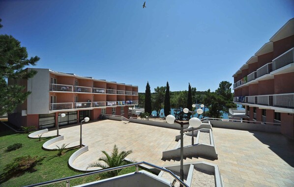 A multi-story hotel with balconies, a central courtyard, and a view of the sea.