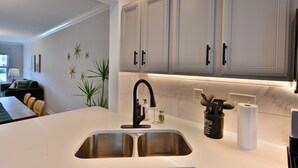 Una cocina moderna con un lavamanos doble, armarios blancos y un salpicadero de mármol.