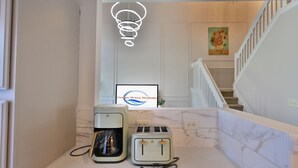 Una zona de cocina con cafetera, tostadora y un logotipo enmarcado en la pared.