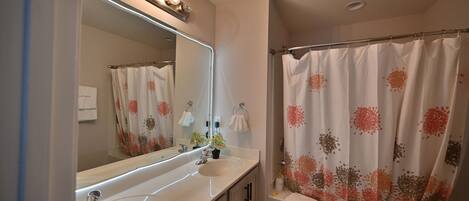 A bathroom with a double sink vanity, a large mirror, and a shower curtain with a floral pattern.