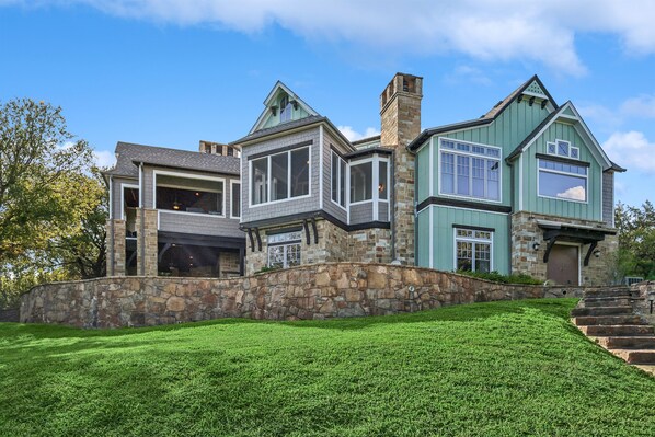 A large, multi-story house with a stone facade, multiple windows, and a stone staircase leading to the entrance. - Sunset Manor- with a DOCK & HOT TUB! (Graham)