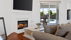 Ein Wohnzimmer mit Kamin, einem darüber hängenden Flachbildfernseher und einem Sofa.