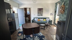 A modern kitchen with a dining area, a sofa, and a decorative rug. - Gîte Du Vieux Chêne (Plaine)