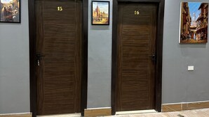 Un pasillo con dos puertas de madera con los números 15 y 16, decorado con cuadros enmarcados.