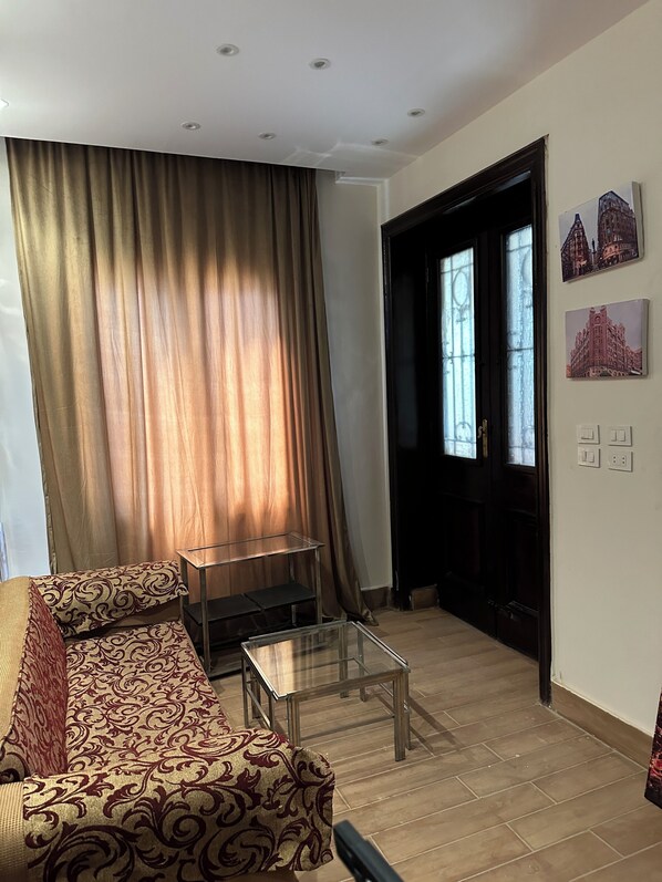 A living room with a sofa, a glass coffee table, and a door leading to another room. - Tahrir square hotel Cairo (Cairo)