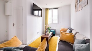 Un salon moderne avec un canapé, une table basse et un téléviseur fixé au mur.