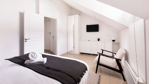Une chambre à coucher moderne avec un lit, une chaise, un bureau et un téléviseur.