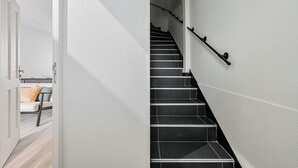 Un escalier avec des marches noires et une rampe, menant à l’étage supérieur.