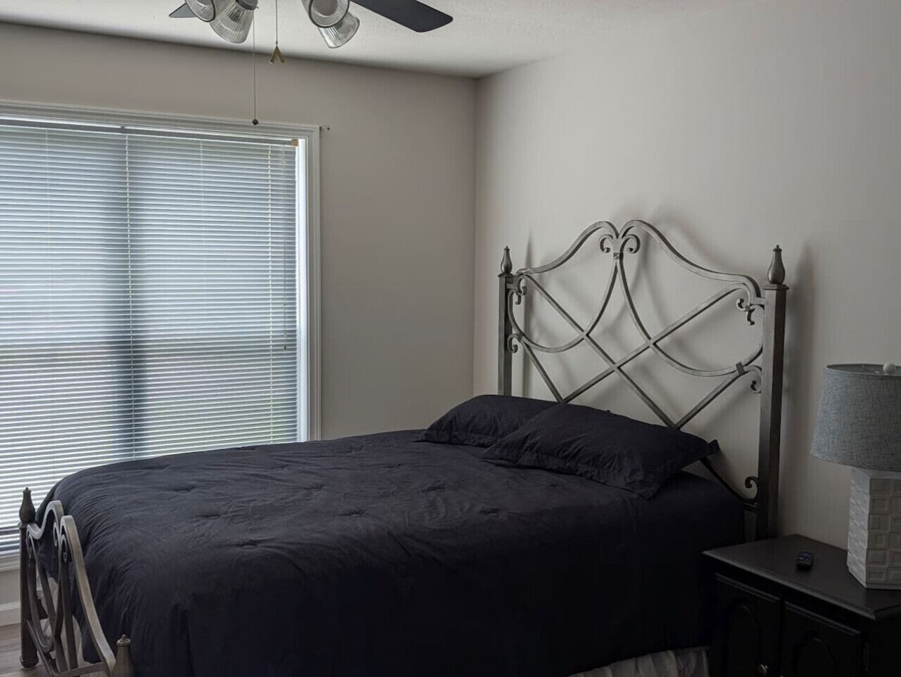 Une chambre à coucher avec un lit, une table de chevet, une lampe et un ventilateur de plafond.