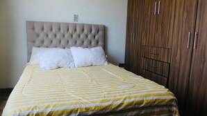 Un letto con copriletto a righe, testata imbottita e cuscini bianchi.