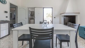 Un comedor con una mesa blanca, cuatro sillas y un jarrón de cristal como centro.