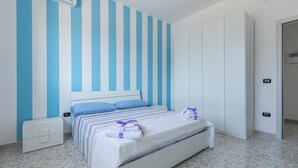 Un dormitorio con una cama, una mesita de noche, un aire acondicionado instalado en la pared y una puerta.