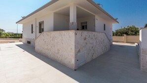 Una casa moderna con techo plano, base de piedra y un porche cubierto.