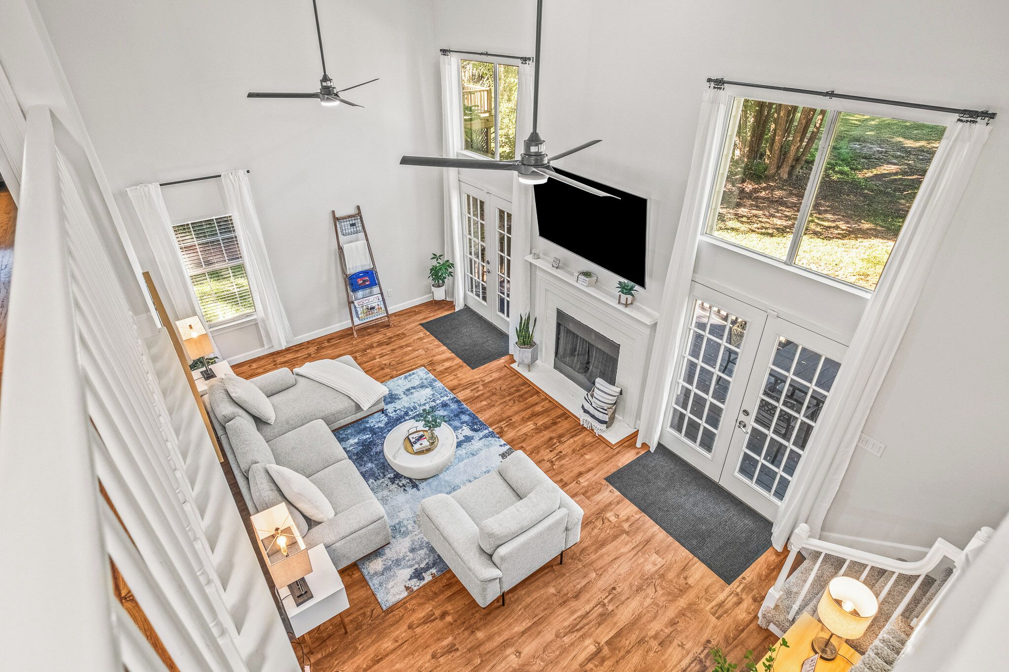 A spacious living room with a fireplace, a large TV, and a ceiling fan.