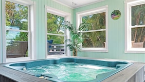Ein Whirlpool in einem Zimmer mit großen Fenstern und Blick auf Bäume.