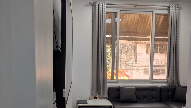 A modern living room with a sectional sofa, a small table, and a bar stool. - New Furn 1 Br/1 Bath/Kitchen, Manila-Univ Belt, AC, Hot water, Wifi, Netflix -u2 (Manila)