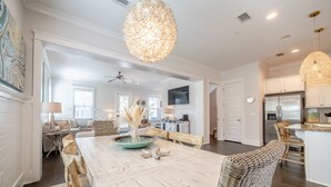 A spacious kitchen with modern appliances, a dining area with a large wooden table, and a cozy living room with a sofa and decorative pillows. - Tiki Tides on 30A!  Summer dates left!  Golf cart included.  🤩🌴  (Santa Rosa Beach)