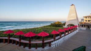 A wooden deck with white chairs and red umbrellas overlooking the ocean. - Tiki Tides on 30A!  Summer dates left!  Golf cart included.  🤩🌴  (Santa Rosa Beach)