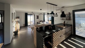 A modern kitchen with a central island, pendant lighting, and a view to the outdoors.