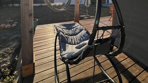 A wooden deck with a hammock and a cushioned swing chair.