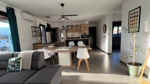 A modern living room with a grey sofa, a coffee table, and a dining area with a kitchen in the background.