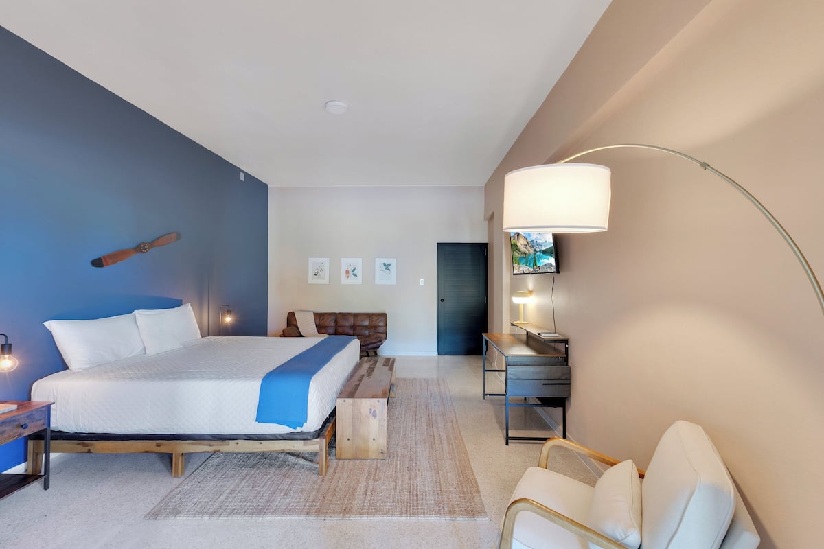A modern bedroom with a large bed, bedside tables, a desk, and a chair.