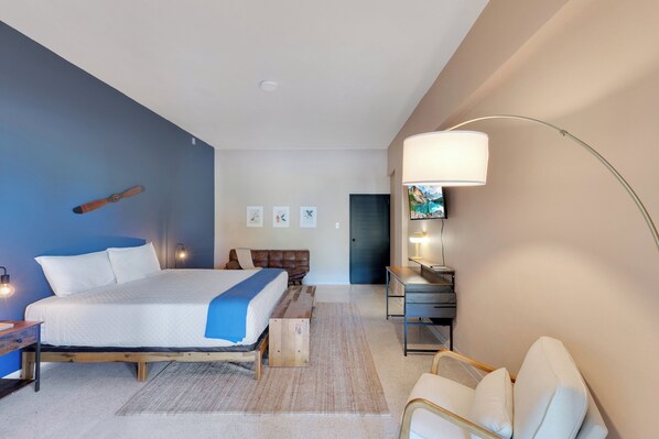 Une chambre à coucher moderne avec un grand lit, des tables de chevet, un bureau et une chaise.