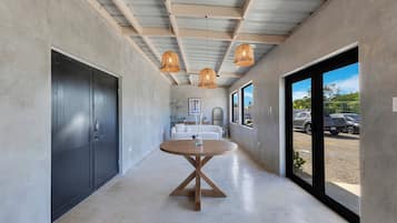 A hallway with a round table, large windows, and hanging lights.
