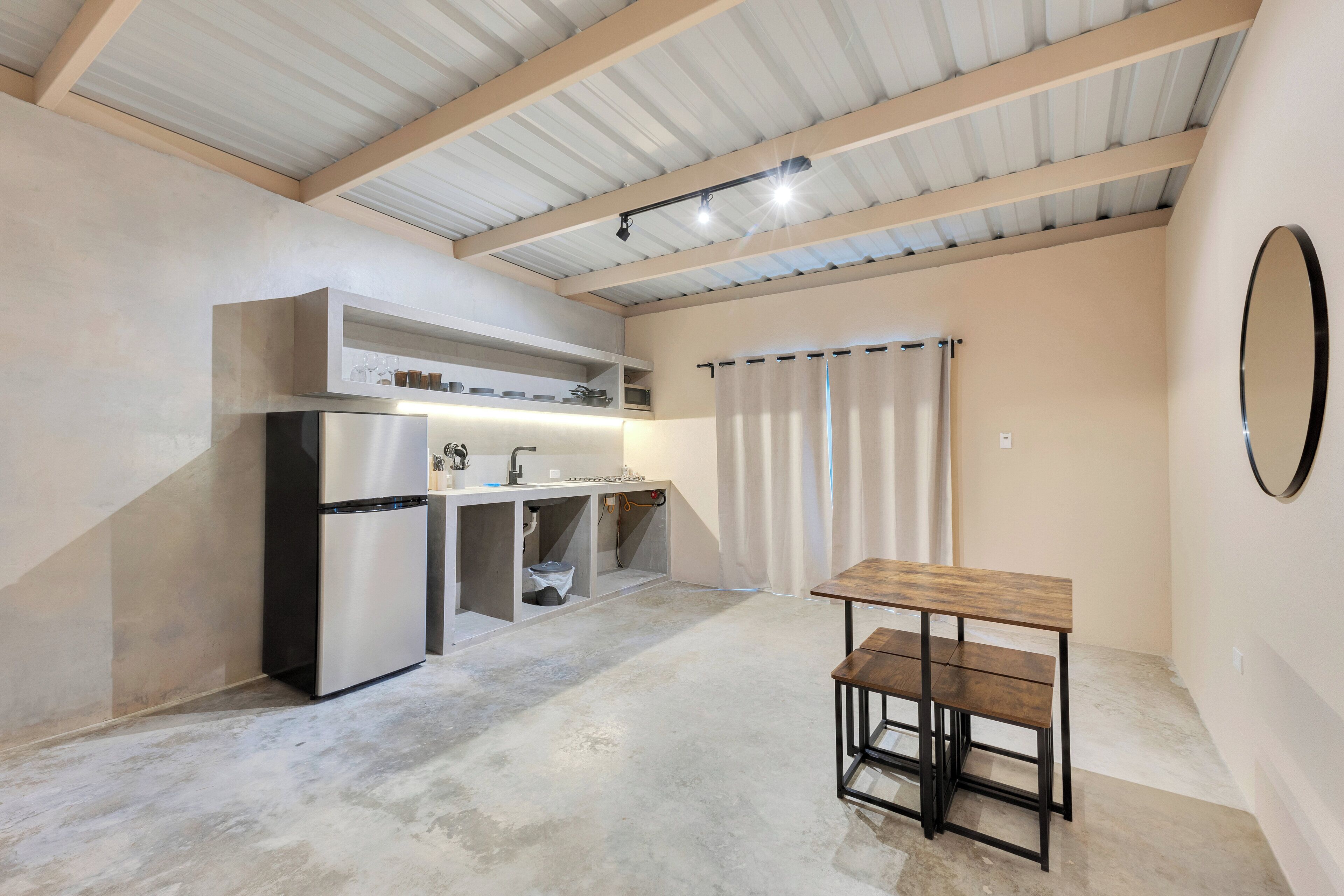 A compact kitchen with a built-in refrigerator, a sink, and a wooden table.
