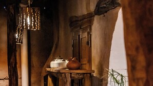 A rustic interior with wooden furniture, a water dispenser, and a vase with plants. - HOSTERIA REFUGIO DEL PINTOR (Tilcara)