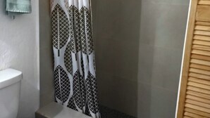 Un baño con cortina de ducha, inodoro y lavamanos.
