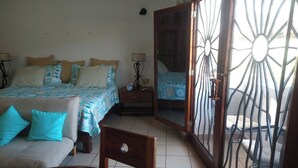 Un dormitorio con cama, sofá, mesa de comedor y balcón con reja de metal.