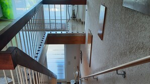 Eine Treppe mit Metallgeländer, Holzhandlauf und einer Wandleuchte.