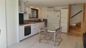 Una cocina moderna con una mesa y sillas de vidrio, horno empotrado y microondas.
