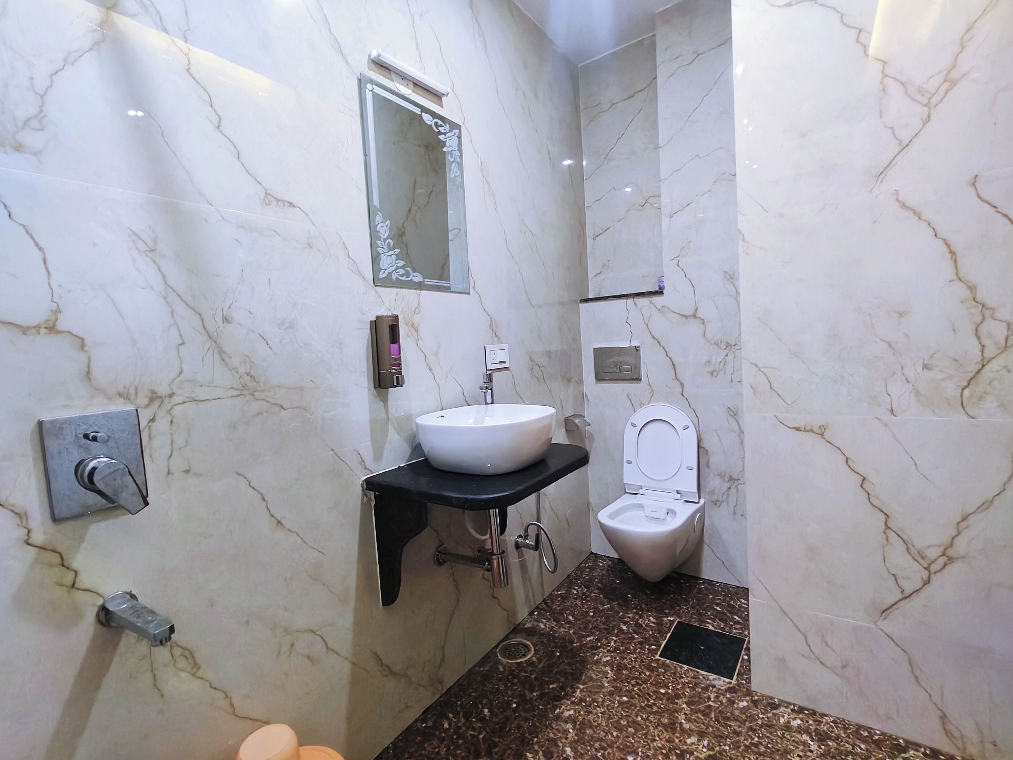 Un bagno con parete in marmo, lavabo, water e specchio.