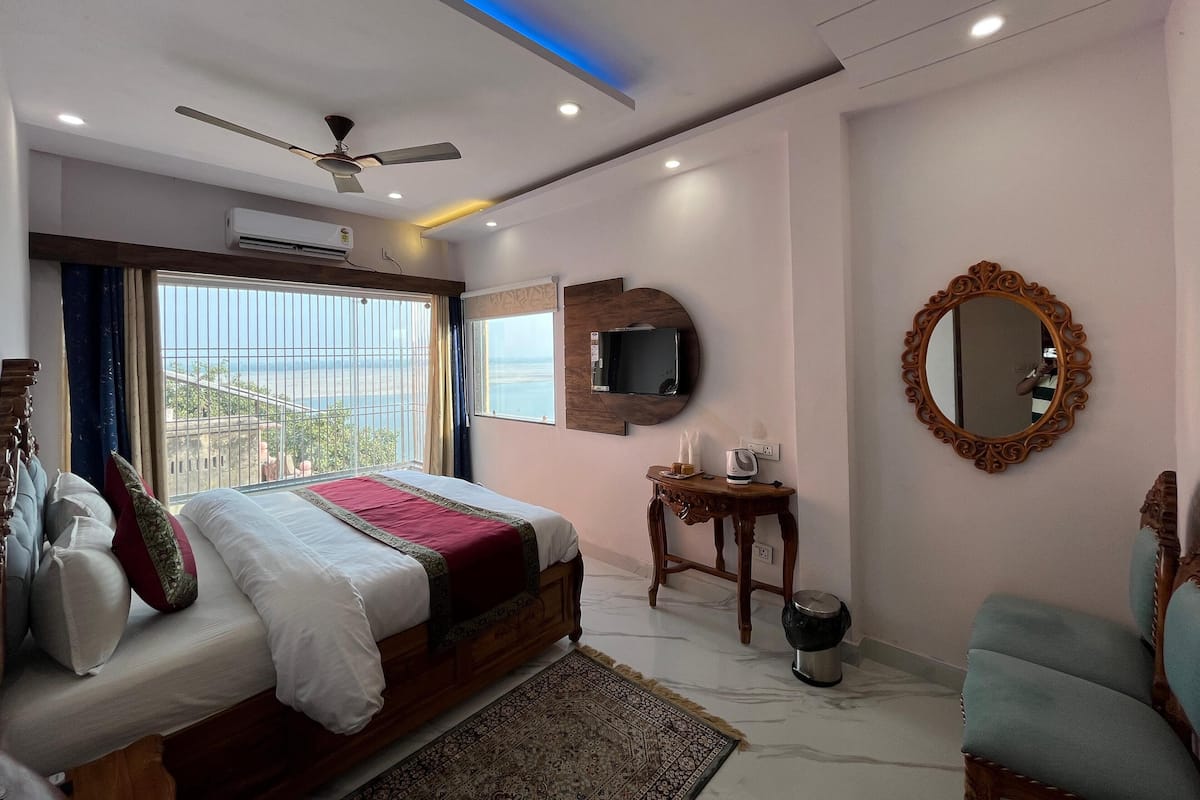 Habitació d'hotel amb llit, ventilador de sostre, televisió, mirall i vista al mar.