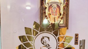 Un mostrador de recepción con un logotipo, un cuadro religioso enmarco y una pared de mármol.