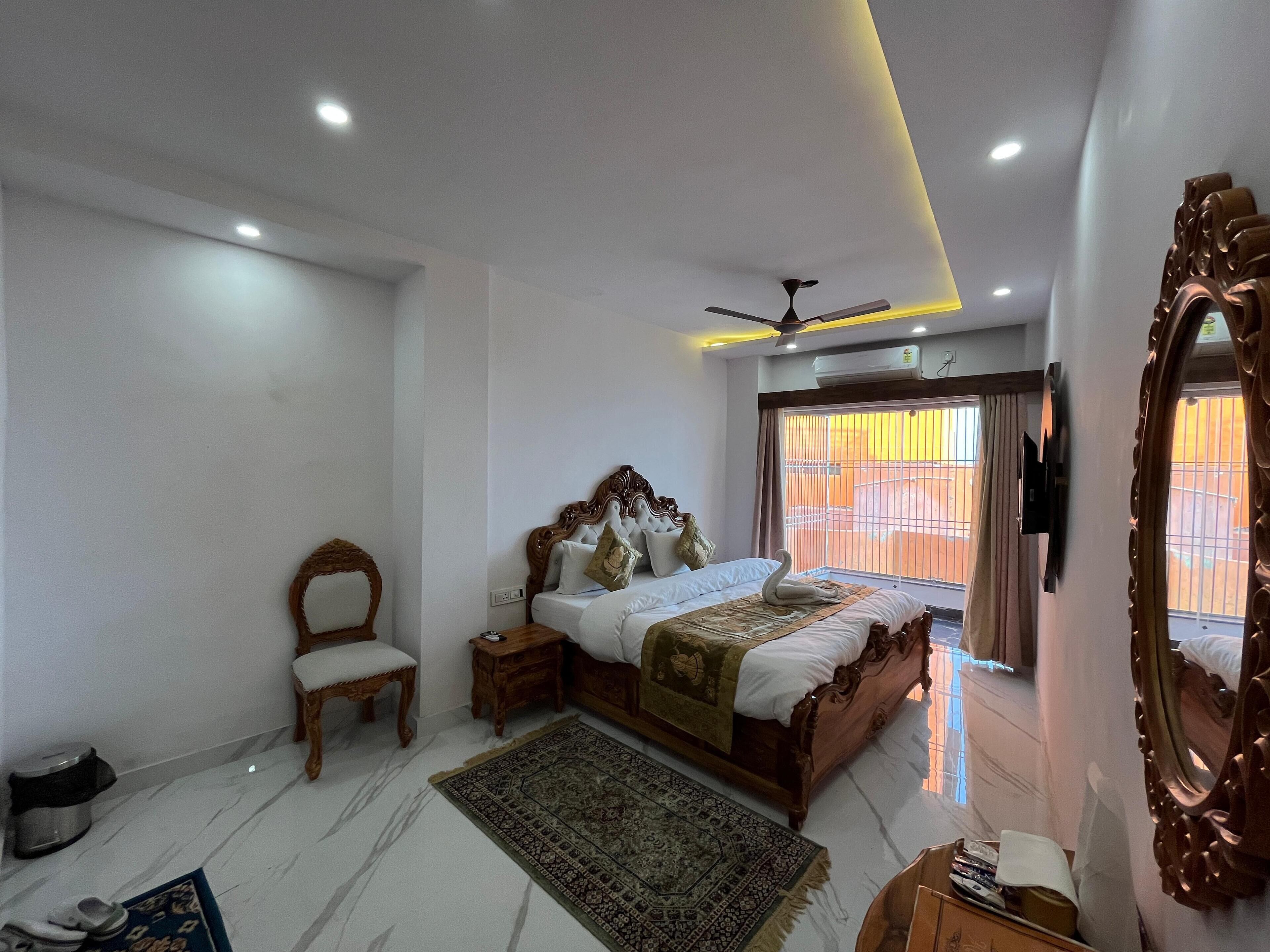 A bedroom with a bed, a chair, a nightstand, a ceiling fan, and a large mirror.