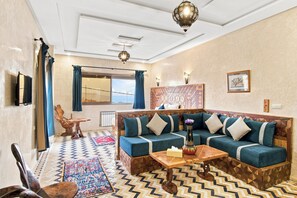 Un soggiorno moderno con un divano, un tavolino da caffè, una poltrona decorativa, un tappeto fantasia e vista sull'esterno.