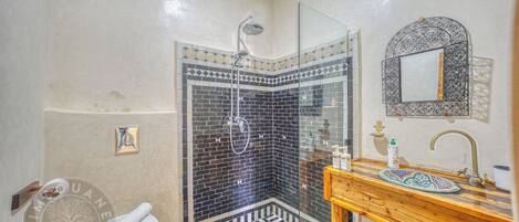 A bathroom with a shower, toilet, sink, and decorative mirror.